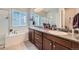 Elegant bathroom featuring double sinks, granite countertops, and a soaking tub by the window at 3630 Gold Bug St, Aurora, CO 80019