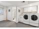 Functional laundry room with white cabinets, utility sink, and modern washer and dryer units at 2437 E Geddes Pl, Centennial, CO 80122