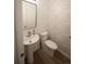 Stylish half bathroom features a pedestal sink, modern toilet, and a neutral, wood-look accent wall at 5462 S Cedar St, Littleton, CO 80120
