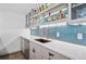 Bar area with an undermount sink and a copper faucet, tile backsplash, and open shelving at 15490 W Asbury Ave, Lakewood, CO 80228
