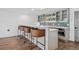 Elegant bar area with seating, sleek cabinetry, open shelving, and a built in oven at 15490 W Asbury Ave, Lakewood, CO 80228
