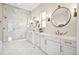 Bright bathroom featuring a marble walk-in shower and dual vanities with modern lighting fixtures at 15490 W Asbury Ave, Lakewood, CO 80228