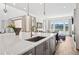 View of kitchen island featuring quartz countertop and sink, adjacent to living area at 15490 W Asbury Ave, Lakewood, CO 80228