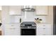 Kitchen showcasing white cabinets, stainless steel oven and range hood, and white backsplash at 3501 W 41St Ave, Denver, CO 80211