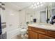 Bright bathroom features a classic wood vanity, ample lighting, and a tiled tub with safety bars at 205 Wright St # 104, Lakewood, CO 80228