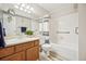 Bright bathroom features a classic wood vanity, ample lighting, and a tiled tub with safety bars at 205 Wright St # 104, Lakewood, CO 80228