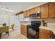 Bright kitchen featuring a dining area with a glass table, wooden cabinets, and stainless steel appliances at 205 Wright St # 104, Lakewood, CO 80228