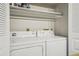 Bright laundry area featuring a white washer and dryer with overhead shelving for storage at 205 Wright St # 104, Lakewood, CO 80228