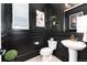 Stylish powder room with black wainscoting, a pedestal sink, a decorative mirror, and modern fixtures at 110 Ferris Ln, Erie, CO 80516