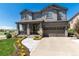 Lovely gray two-story home with a welcoming front porch, stone details, and a beautifully landscaped front yard at 110 Ferris Ln, Erie, CO 80516