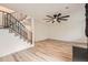Bright living room with light wood floors, a decorative ceiling fan, and staircase with black ornamental iron railing at 12010 E Harvard Ave, Aurora, CO 80014