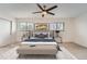 This staged main bedroom has neutral carpet and paint, two windows, and a large ceiling fan at 12010 E Harvard Ave, Aurora, CO 80014