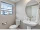 Contemporary bathroom with pedestal sink, round mirror, and a window providing natural light at 1990 S Holly St # 4, Denver, CO 80222