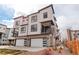 Modern three-story townhome with white siding, stone accents, and two-car garage at 1990 S Holly St # 4, Denver, CO 80222