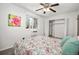 Bright bedroom features a ceiling fan, window, closet, colorful painting, and bed with floral comforter at 8060 W 9Th Ave # 204, Lakewood, CO 80214