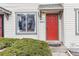 Close-up view of a townhouse entrance featuring a vibrant red door and a well-maintained green shrub at 17694 E Loyola Dr # C, Aurora, CO 80013