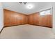 Unfinished basement area showing carpeted floors and wood panel walls at 701 W Quincy Ave, Englewood, CO 80110