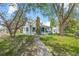 A quaint, two-story home with a brick chimney, framed by mature trees and a winding walkway at 701 W Quincy Ave, Englewood, CO 80110