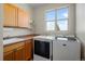 Well-lit laundry room with a large window, modern washer and dryer, sink and cabinets for storage at 1505 Legacy Trl, Elizabeth, CO 80107