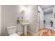 Charming powder room featuring a pedestal sink, oval mirror, and adjacent hallway view at 15402 E 113Th Pl, Commerce City, CO 80022