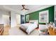 Bedroom with a bold green accent wall, fan, and a barn door leading to the ensuite bathroom at 15402 E 113Th Pl, Commerce City, CO 80022