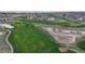 An aerial view of a meticulously manicured golf course with lush green fairways and strategically placed sand traps at 15402 E 113Th Pl, Commerce City, CO 80022