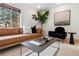 Living room with light brown couch, dark blue chairs, and large window at 936 Eudora St # 102, Denver, CO 80220