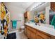 Well-lit bathroom with a large mirror, wood vanity, and shower-tub combination at 1115 Cherry Ct, Fort Lupton, CO 80621