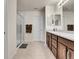 Well-lit bathroom featuring a double sink vanity, a large mirror, and a glass-enclosed shower with tiled walls at 9844 Truckee St, Commerce City, CO 80022