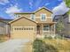 Two-story home with tan siding, a two-car garage, and a charming front porch at 9844 Truckee St, Commerce City, CO 80022