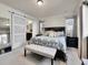 Spacious main bedroom featuring a bed frame, bench seat, and a view into the attached ensuite bathroom at 9844 Truckee St, Commerce City, CO 80022