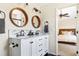 Bathroom featuring a double vanity with round wood mirrors, and tiled shower with glass door at 3962 Hoyt Ct, Wheat Ridge, CO 80033