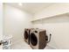 Modern laundry room featuring front loading washer and dryer, plus a convenient storage shelf at 24505 E Ada Pl, Aurora, CO 80018