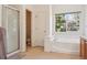 Bright bathroom featuring a soaking tub, a walk-in shower, and a window with views of trees at 10795 Quail Creek E Dr, Parker, CO 80138