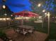 Inviting back yard at night with patio under lighted umbrella and string lights creating a cozy ambiance at 6731 Devinney St, Arvada, CO 80004