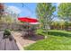 Backyard with a red umbrella over an outdoor dining area, and a healthy green lawn at 6731 Devinney St, Arvada, CO 80004