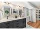 Bathroom featuring a double vanity with oval mirrors, hardwood floors, and a window with bright natural light at 6731 Devinney St, Arvada, CO 80004