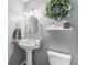 Charming powder room with a pedestal sink, decorative mirror, and elegant wreath at 6731 Devinney St, Arvada, CO 80004