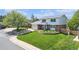 Charming two-story home featuring a well-manicured front yard with an inviting garden and mature trees at 6731 Devinney St, Arvada, CO 80004