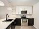 Modern kitchen with stainless steel appliances, white quartz countertops, and contemporary black and white cabinetry at 6133 S Sterne Cir, Littleton, CO 80120