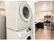 Convenient laundry area with stacked washer and dryer, situated adjacent to a modern kitchen at 6133 S Sterne Cir, Littleton, CO 80120