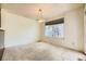 Empty living room with neutral walls, carpeted floors, and a large window with a tree view at 2370 Redwood Ave, Lafayette, CO 80026