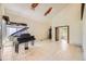 Bright living room featuring soaring ceilings, tile floors, and a black baby grand piano under a window at 2370 Redwood Ave, Lafayette, CO 80026