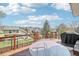 Wide angle view of deck with table and grill with a view of fenced backyards and blue skies at 11035 W Grand Pl, Littleton, CO 80127