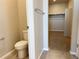 Well-lit bathroom with a toilet, towel rack, tile flooring, and a view into the walk-in closet at 8945 Rifle St, Commerce City, CO 80022