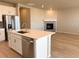 Modern kitchen with stainless steel appliances, white cabinets, island with quartz countertops, and a view of the fireplace at 8945 Rifle St, Commerce City, CO 80022