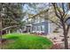 Landscaped backyard of gray home with lawn, stone pathway, mature trees, and outdoor seating at 5459 E Dry Creek Cir, Centennial, CO 80122