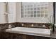 Bright bathroom with a soaking tub, marble tile accents, a glass block window, and neutral colored walls at 2587 S Harlan Ct, Lakewood, CO 80227