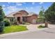 Attractive brick home featuring a manicured lawn, mature trees, and a curved driveway leading to the garages at 2587 S Harlan Ct, Lakewood, CO 80227