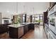 Open concept kitchen with a marble countertop island, hardwood floors, stainless steel dishwasher and connection to the living room at 2587 S Harlan Ct, Lakewood, CO 80227